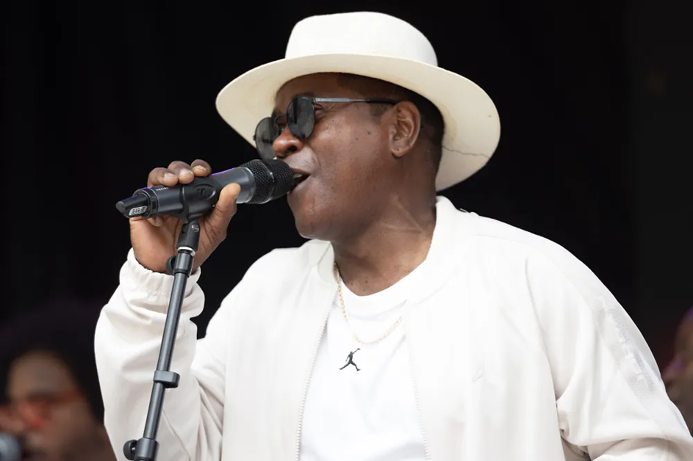 Vocalist in a white suit and hat singing into a microphone, the kind of client-recognizable face the processor handles without touching a server.
